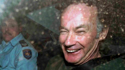 Nesta foto de arquivo de 4 de novembro de 1997, Ivan Milat sorri em um carro da polícia após comparecer a um tribunal em Sydney.
