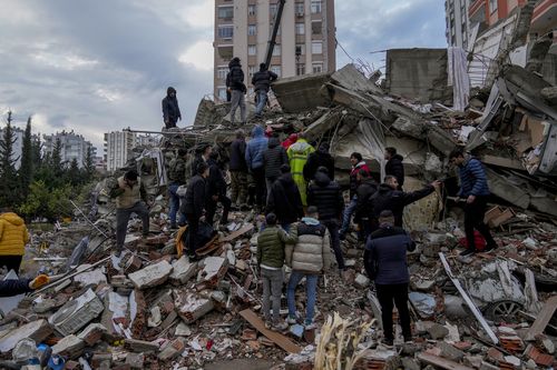 People and emergency teams search for people in a destroyed building in Adana, Turkey, Monday, Feb. 6, 2023.  