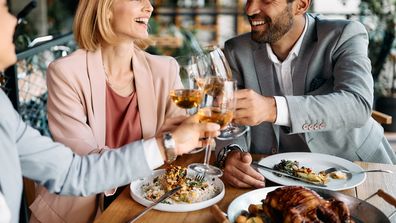 Group of happy colleagues having fun and toasting with wine while having business lunch in a restaurant.