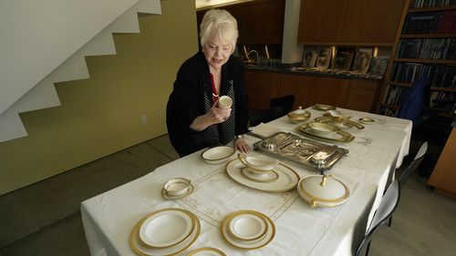 HOLD TO MOVE THURSDAY AUG 26 WITH STORY Diane Capone looks over one of the pieces of the china set that once belonged to her grandparents, Mae and Al Capone, on display at Witherells Auction House in Sacramento, Calif., Wednesday, Aug. 25, 2021. The granddaughter of the famous mob boss, she and her two surviving sisters will sell 174 family heirlooms at an Oct. 8 auction titled A  Century of Notoriety: The Estate of Al Capone, that will be held by Witherells in Sacramento. (AP Photo/Rich Pedronc