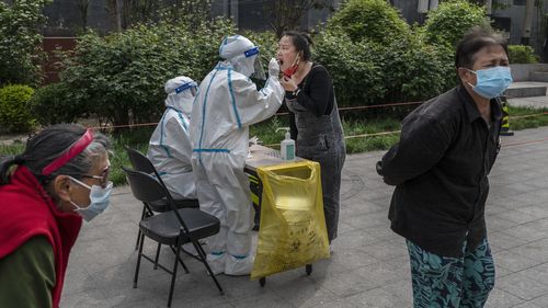 Una mujer se somete a una prueba de ADN de COVID-19 cuando las autoridades de Beijing anunciaron que realizarán una prueba masiva en medio de un nuevo brote del virus. 