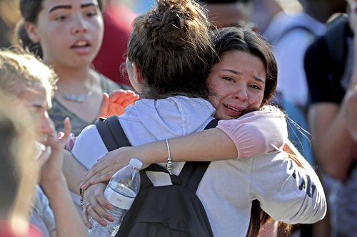 Outside the school, friends hug each other in shock and relief. Picture: AAP