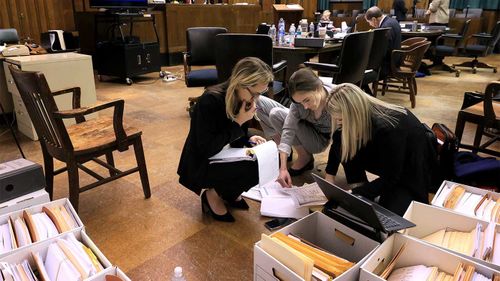 Attorneys Lindsay Runnels and Kylie Mank and paralegal Maci Morgan search through boxes of exhibits before court restarts after a break for lunch during the fourth day of Lamar Johnson's wrongful conviction hearing.