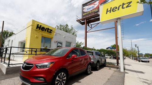 Rental vehicles parked outside a closed Hertz car rental office in Denver.