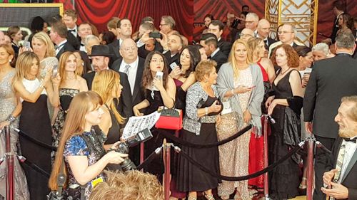 Audience members wait behind the red carpet cordon. (9NEWS/Ehsan Knopf)