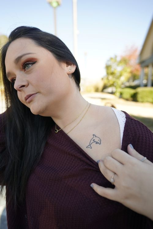 Lindsey Kirk shows a tattoo on her neck that commemorates her late mother's favorite animal, a dolphin.