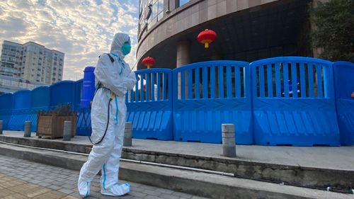 A worker in protectively overalls and carrying disinfecting equipment walks outside the Wuhan Central Hospital, China.