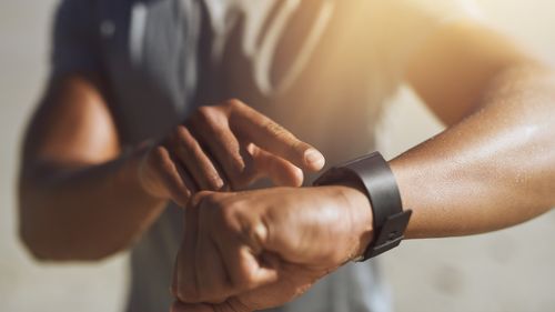 Closeup shot of a man checking his smartwatch while exercising outdoors.