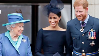 Queen Elizabeth, Meghan, Duchess of Sussex and Prince Harry, Duke of Sussex watch a flypast to mark the centenary of the Royal Air Force from the balcony of Buckingham Palace on July 10, 2018 in London, England. 