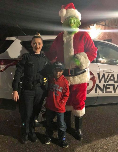 Tylon poses with Officer Develle and an actor dressed as the Grinch. (Facebook/TeDera Dwayne Graves II)