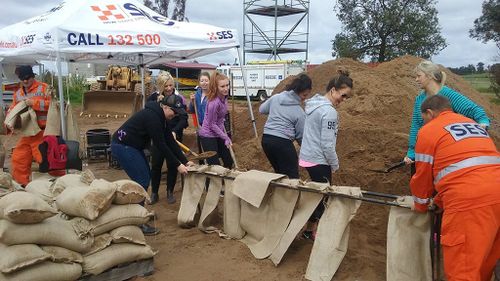 Local residents assist SES volunteers in filling sand bags in Forbes. (AAP)