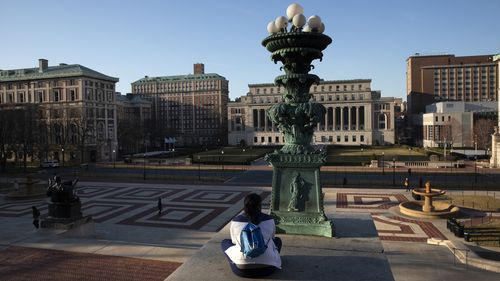 A woman sits on the Columbia University campus, Monday, March 9, 2020 in New York.