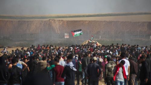 Smoke rises in the air as Palestinian protesters gather for a demonstration near the Gaza-Israel border, on Friday, April 6, 2018. (AAP)