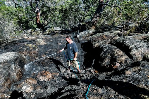 Residents were forced to brandish garden hoses to fight off spot fires near their homes in Menai, which left hectares of bushland blackened. Picture: 9NEWS.