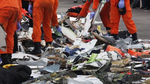 Indonesian rescue team members collecting the remains of the crashed plane at Tanjung Priok Harbour.