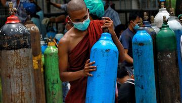  In this July 28, 2021, file photo, Buddhist monk wearing a face mask holds an oxygen tank for refill outside the Naing oxygen factory at the South Dagon industrial zone in Yangon, Myanmar. 