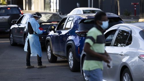 A medical worker takes drivers' details in the line for a drive-through testing clinic in Blacktown, Sydney. 