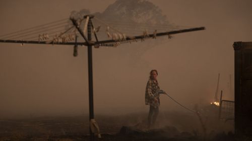 Clair Cowie defends her home from an out of control spot fire on February 01, 2020 at Bredbo North near Canberra, 