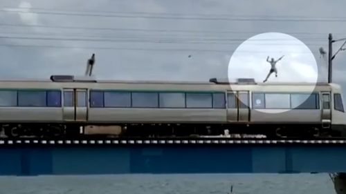 The man can be seen balancing on the train, even waving to the camera before making the horrifying jump. (Facebook)