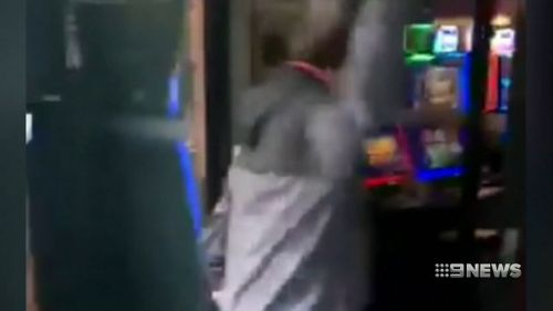 A man was filmed smashing the poker machines with a hammer and a meat cleaver. (9NEWS)