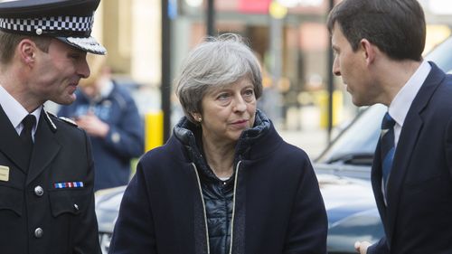 Britain's Prime Minister Theresa May, centre, is briefed by members of the police as she views the area where former Russian double agent Sergei Skripal and his daughter were found critically ill, in Salisbury, England,