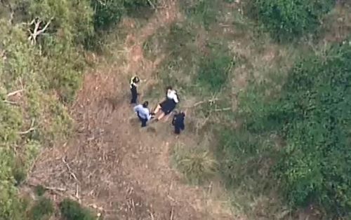 One of the two men arrested is handcuffed by police in Daylesford. (9NEWS)