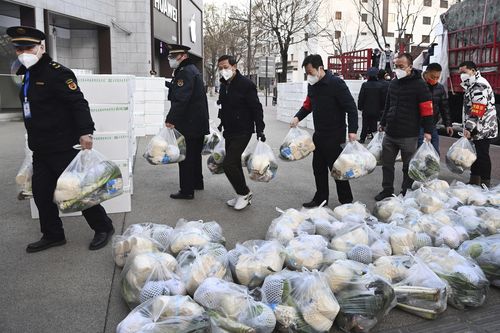 In this photo released by Xinhua News Agency, subdistrict office staff carry daily necessities to be delivered to households under closed-off management in Xi'an, in northwestern China's Shaanxi Province, Dec. 29, 2021. Chinese officials promised steady deliveries of groceries to residents of Xian, an ancient capital with 13 million people that is under the strictest lockdown of a major Chinese city since Wuhan was shut early last year at the start of the pandemic. (Liu Xiao/Xinhua via AP)