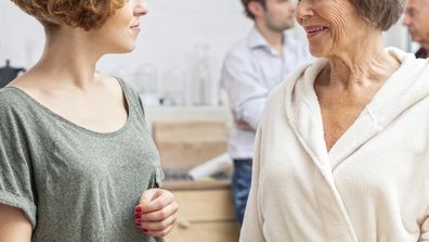 A wife seeks advice from her mother-in-law first thing in the morning while her husband and father-in-law are in the background.