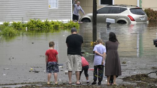 Residents check on one another in a flooded neighborhood in the aftermath of Hurricane Ian, Thursday, Sept. 29, 2022, in Orlando, Fla. (AP Photo/Phelan M. Ebenhack