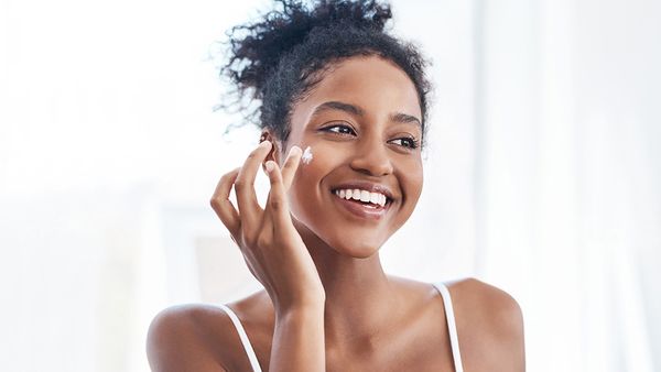 Shot of a beautiful young woman applying moisturiser to her face in the bathroom at home