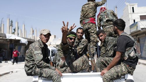 Members of YPG flashing victory sign after coming from Syrian town of al-Raqqa, in Syria. (AAP)