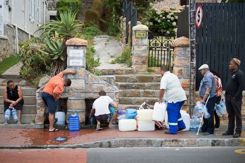 People collect drinking water from pipes fed by an underground spring, in Cape Town on January 19, 2018, as the city battled its worst drought in a century.