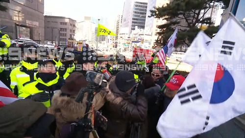 South Korean flags flew during the protest. Athletes from the North and the South will march under a unified flag at the Games. (9NEWS)