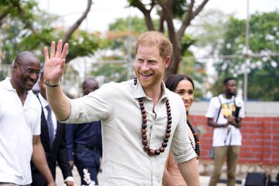 Prince Harry gestures as he and Meghan visit children at the Lights Academy in Abuja, Nigeria, Friday, May 10, 2024.   