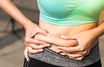 Woman in active wear pinching stomach