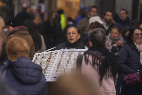 A Christmas lottery seller looks for customers in a crowded street in Madrid, Spain, Sunday, Dec. 3, 2023. 