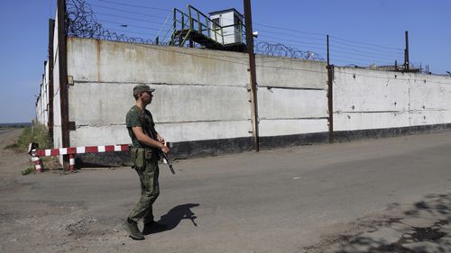 A soldier stand guard next to a wall of a prison in Olenivka, in an area controlled by Russian-backed separatist forces, eastern Ukraine, Friday, July 29, 2022. Russia and Ukraine accused each other Friday of shelling a prison in a separatist region of eastern Ukraine, an attack that reportedly killed dozens of Ukrainian military prisoners who were captured after the fall of a southern port city of Mariupol in May. (AP Photo)