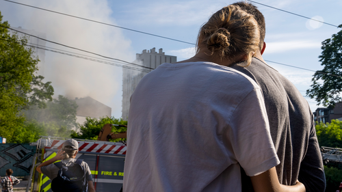 A couple embrace as they look at smoke billowing the air from residential buildings following explosions, in Kyiv, Ukraine, Sunday, June 26, 2022.