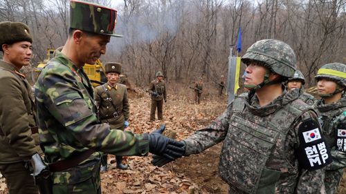 soldiers from the two Koreas shake hands as they gather at Arrowhead Ridge, a site of fierce battles in the 1950-53 Korean War, to build a tactical road across the Military Demarcation Line inside the Demilitarized Zone (DMZ).