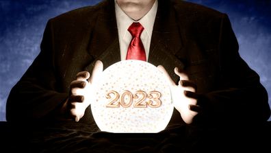 Psychic with hands around fortune telling ball, 2023 written inside in gold letters.
