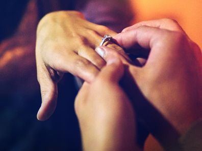 Man placing ring on woman's finger