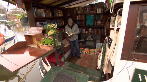 Jon Privett inside his floating bookstore. (9NEWS)