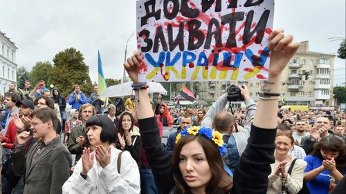 A girl holds a placard which reads 'Enough surrender the Ukraine!' during a rally in front of Ukrainian Defence Ministry in Kiev on August 28.
