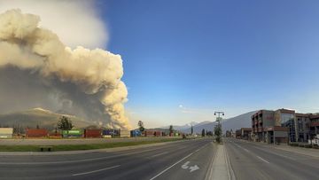In this photo released by the Jasper National Park, smoke rises from a wildfire burning near the resort town.