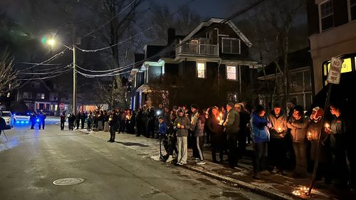 A crowd of people holding candles gather outside the home of Massachusetts Institute of Technology professor Nuno F.G. Loureiro. The Portuguese-born professor was shot and killed on Monday.