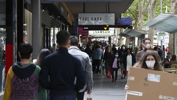 Shoppers walk past stores on Swanston Street in Melbourne. 