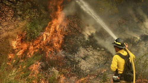 A firefighter puts out a hot spot along Highway 38 northwest of Forrest Falls, California, as the El Dorado Fire continues to burn Thursday afternoon, September 10, 2020