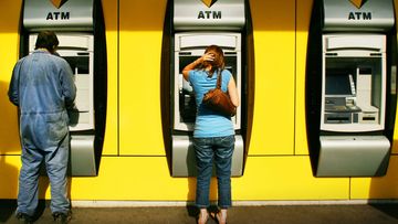 A man and woman withdraw money from a Commonwealth Bank ATM