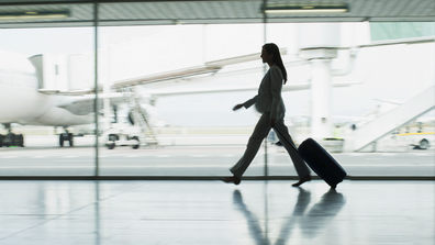 Woman business traveller walks with luggage at the airport