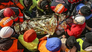 Turkish rescue workers carry Eyup Ak, 60, to an ambulance after pulling him out alive from a collapsed building, 104 hours after the earthquake, in Adiyaman, Friday, Feb. 10, 2023. 